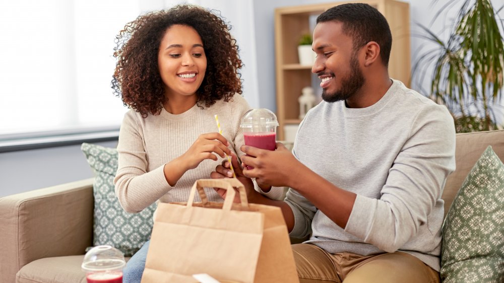 A couple with takeout smoothies sitting on a couch