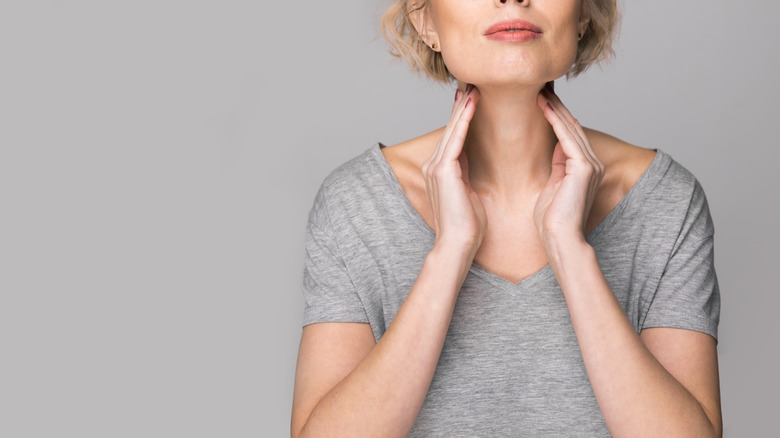 Woman in gray shirt touching the sides of her neck