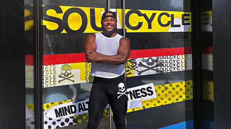 Kamelle Mills stands outside in front of a yellow SoulCycle sign