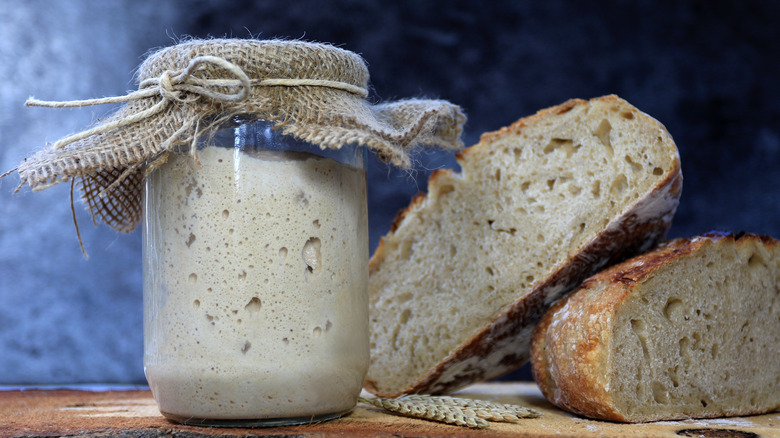 A jar of sourdough starter and sliced sourdough bread