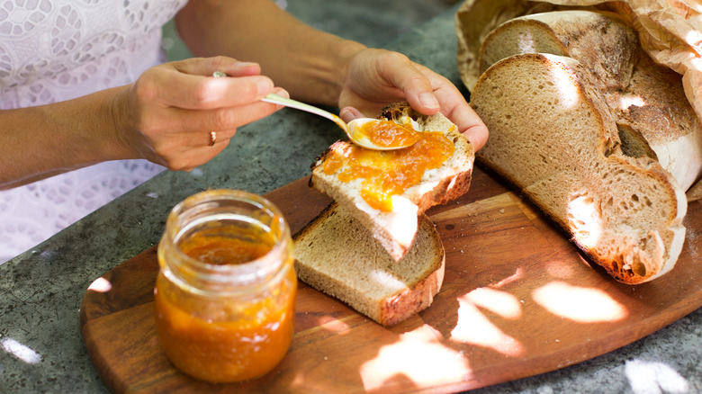 woman speading jam on sourdough bread