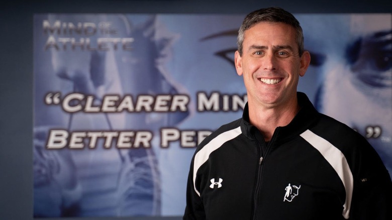 Dr. Jarrod Spencer standing in front of a promo sign for his book