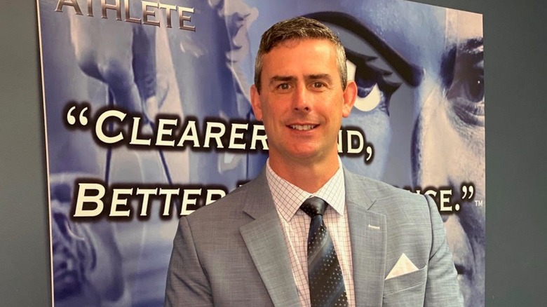 Dr. Jarrod Spencer standing in front of a promo sign for his book