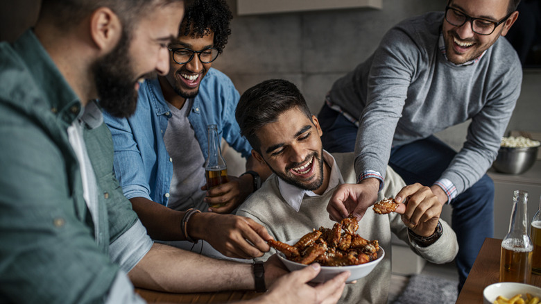 group of men eating chicken wings