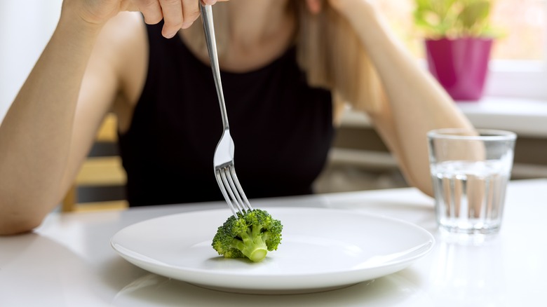 woman prods broccoli with her fork