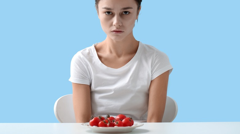 thin woman with plate of tomatoes