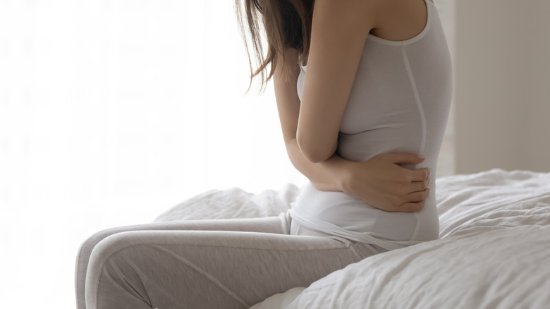 Underweight young woman sits on bed