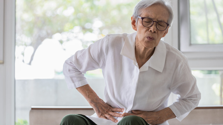 Man clutching stomach while sitting