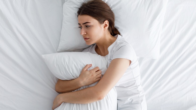 woman hugging pillow in bed