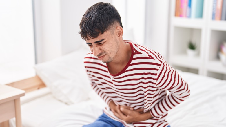 Man clutching stomach on bed