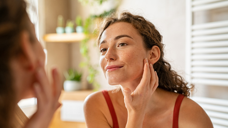 A woman touches her face