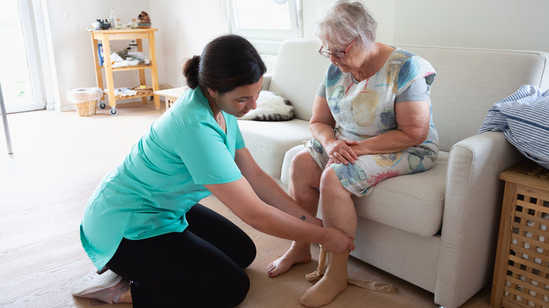 Healthcare provider putting compression socks on patient