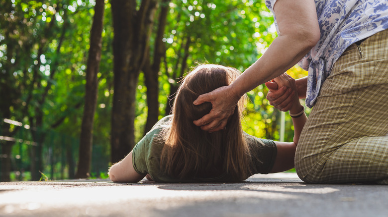 Older woman helping girl that fainted