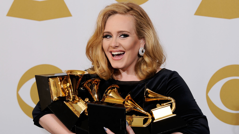 Adele smiling and holding her six Grammys