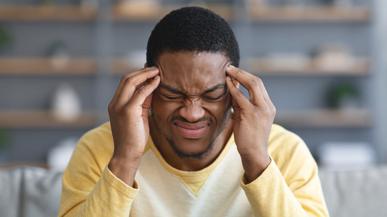 man in pain pressing fingertips on both temples