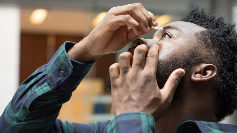 man applying eye drops to eye