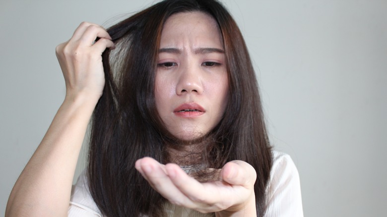 woman frowning at shedding hair in hand