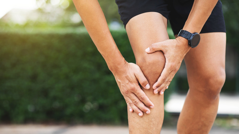 man grabbing knee with both hands