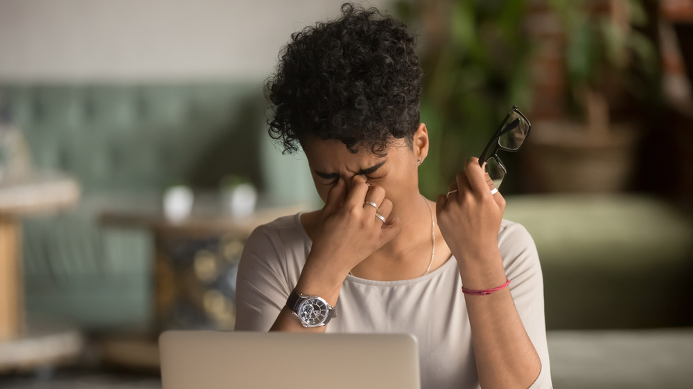 woman at computer rubbing eyes