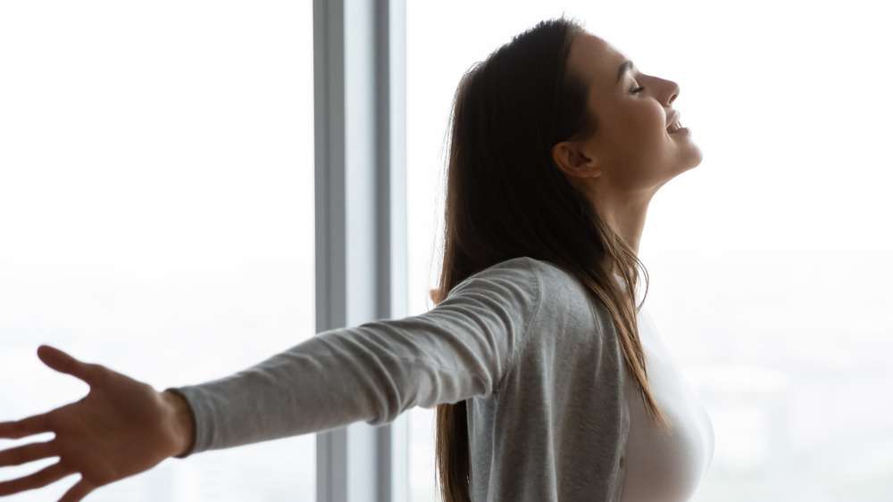 Woman with outstretched arms by a window