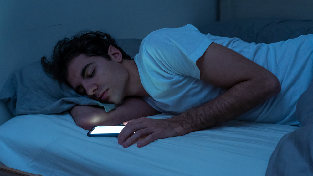 man in bed asleep with a smartphone in hand