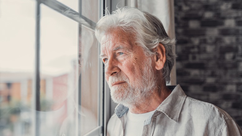 Elderly man looking out of window