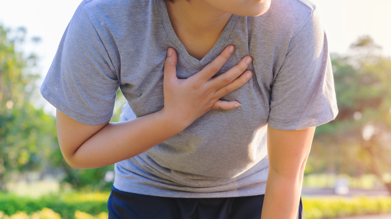 woman holding chest outside