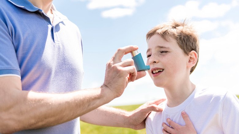 Boy with asthma using an inhaler outside in the sun