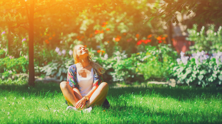 happy woman sitting with her face turned toward the sun