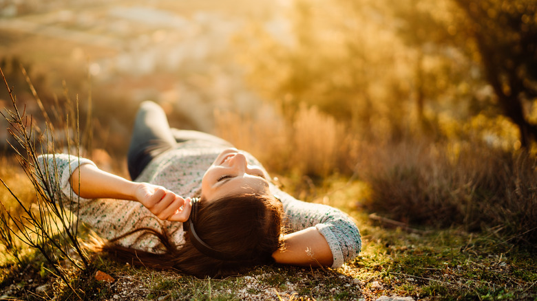 happy woman lying in grass under the sun