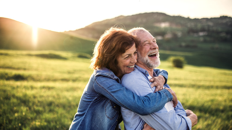 Older couple hugging outside in the sunshine