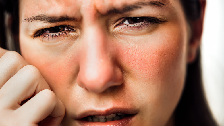 frowning woman with flushed red cheeks