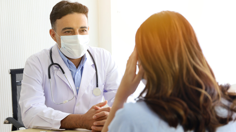 masked doctor consulting with patient