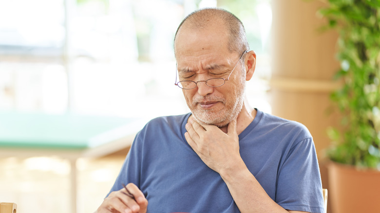 man clutching throat with hand