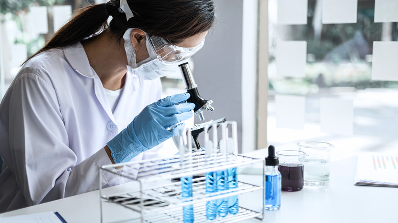 research scientist looking through microscope