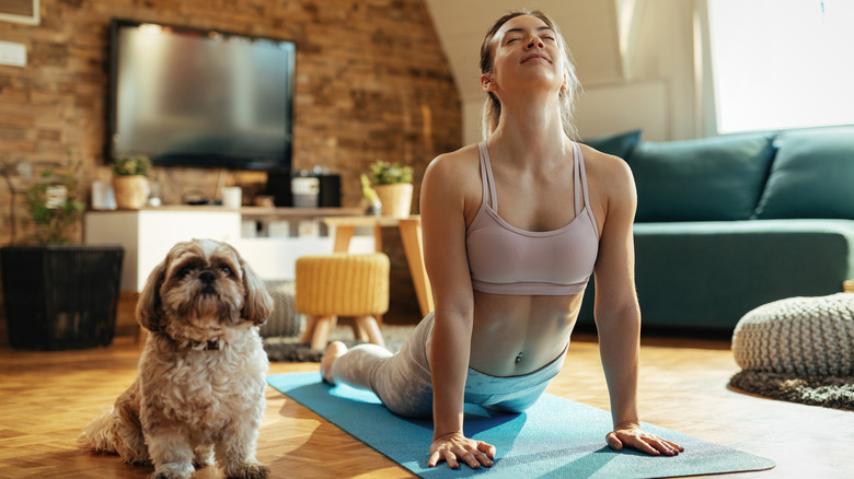 woman doing cobra pose with dog