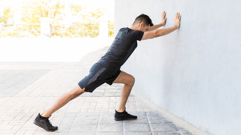 man doing lunging calf stretch