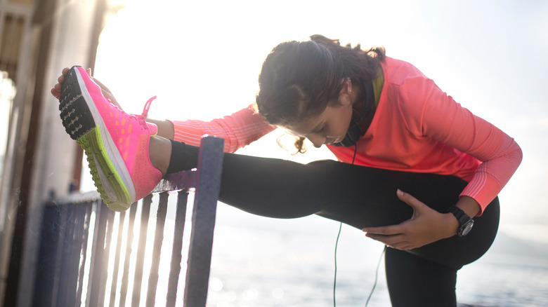 woman stretching her hamstring on a railing