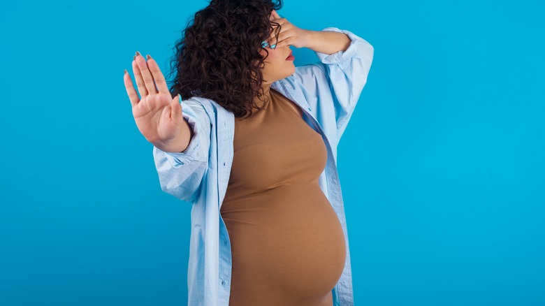 Pregnant woman making STOP gesture