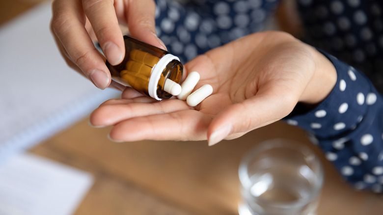 woman pours pills into hand