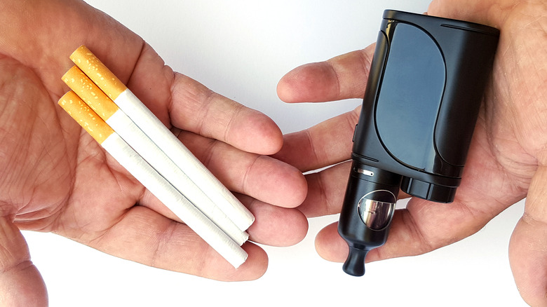 vaping product and cigarettes in a man's hands