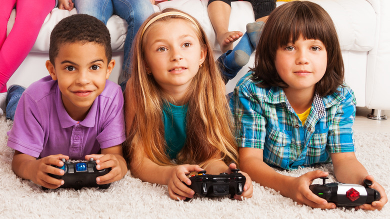 Three young children playing video games 