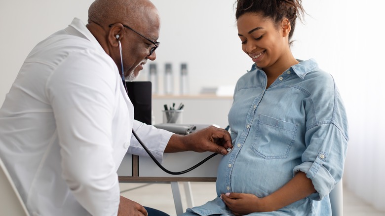 doctor using stethoscope on pregnant woman 