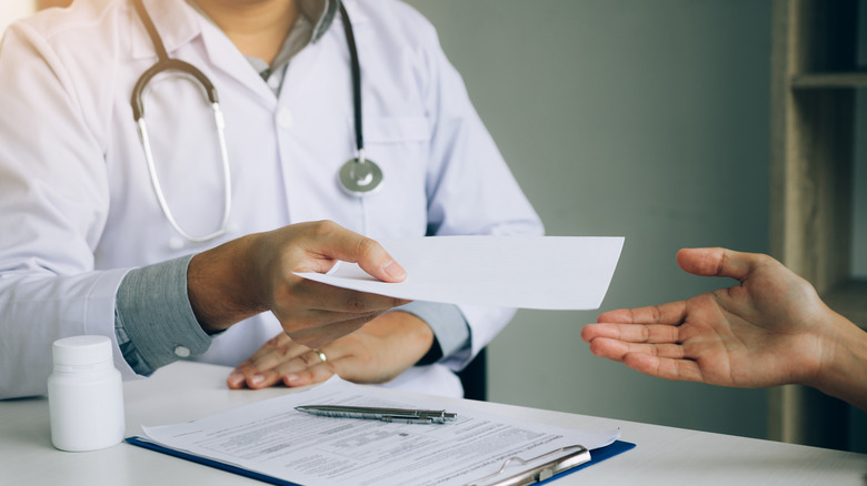 Doctor handing patient prescription slip