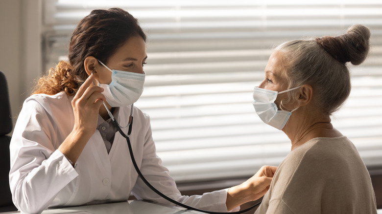 doctor auscultating the heart of elderly Caucasian woman