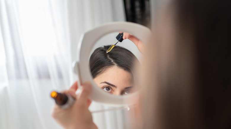 Woman applying oils to scalp