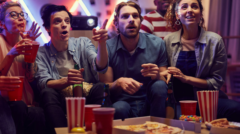 people gathered to watch something on tv and eat