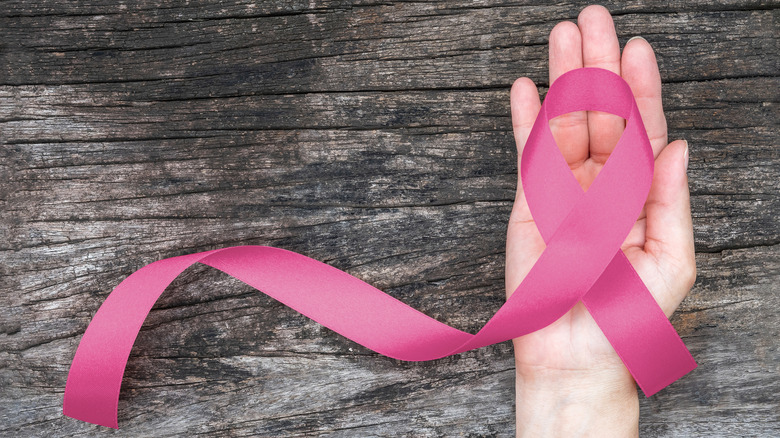 a hand holding a pink breast cancer awareness ribbon