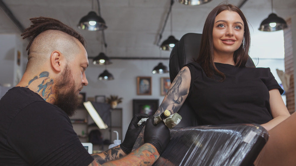 woman being tattooed