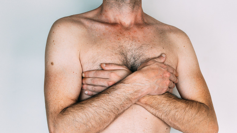bare chested man with hands on chest